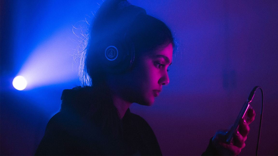 Femme écoutant de la musique dans une pièce sombre.